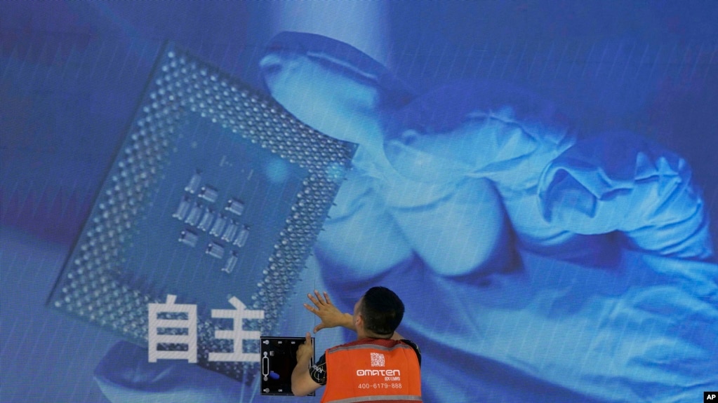 一名工人在上海举办的世界人工智能大会上检查中国科技公司中科曙光展示的芯片和自主字样的屏幕 ...